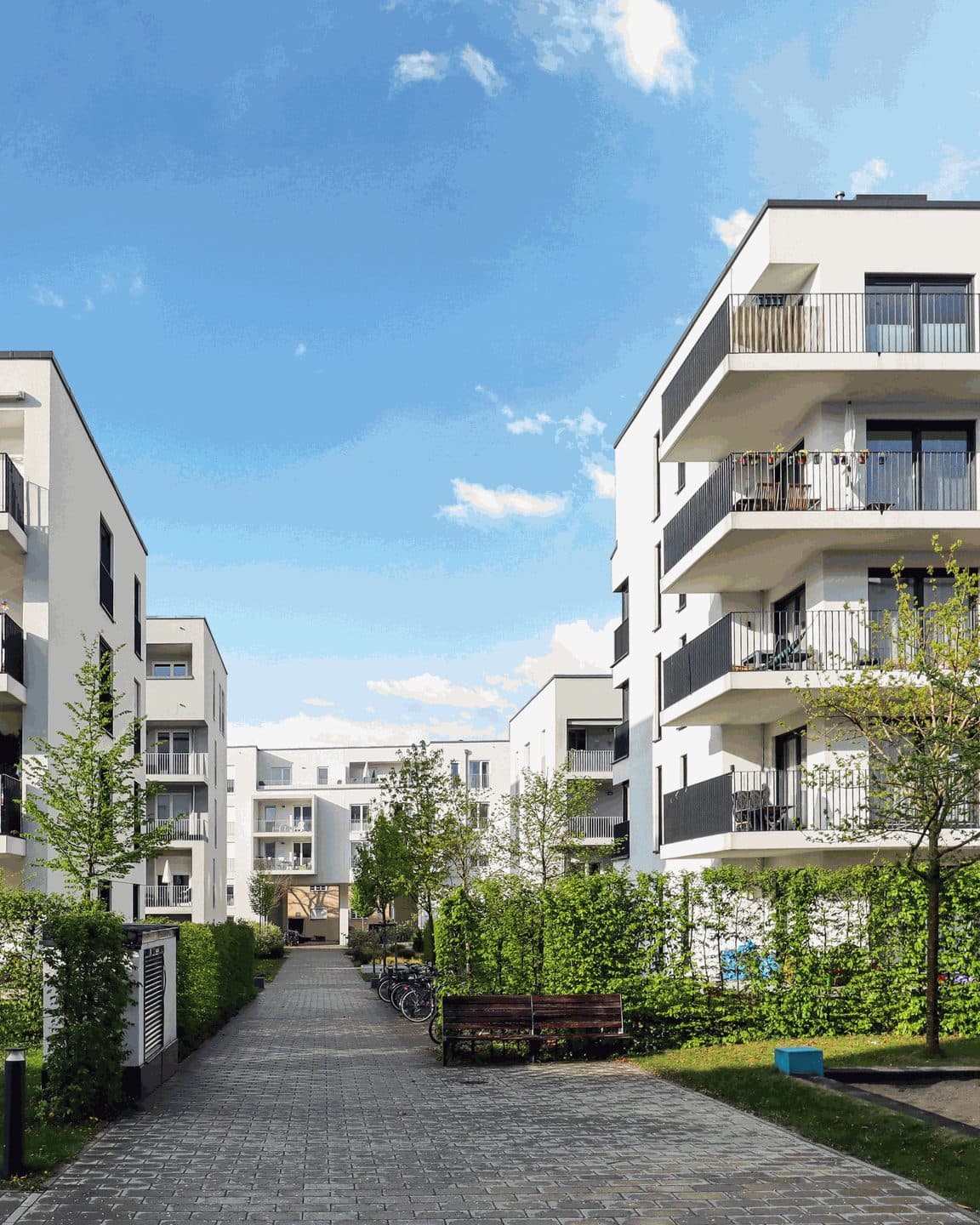 Contemporary white apartment buildings with balconies along a landscaped path
